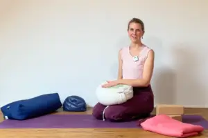 Die Yogalehrerin Anna Sophie Pietsch sitzt auf einer Yogamatte und begrüßt die Teilnehmerinnen ihrer Online-Membership