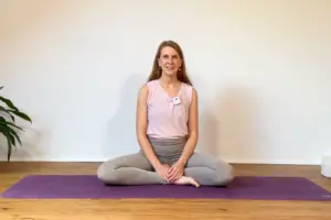 Die Yogalehrerin Anna Sophie Pietsch sitzt auf einer lila Yogamatte.