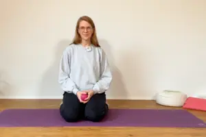 Die Yogalehrerin Anna Sophie Pietsch erklärt eine Übung zur Dammpunkt Massage mit dem pinken Togu Ball, den sie hier in der Hand hält