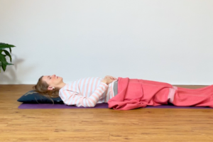 Die Yogalehrerin Anna Sophie Pietsch liegt zugedeckt auf einer Yogamatte.