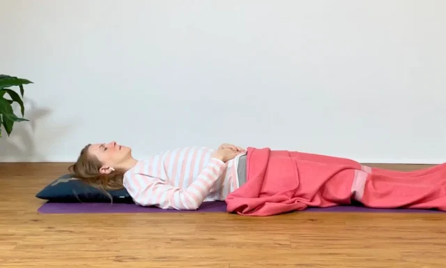 Die Yogalehrerin Anna Sophie Pietsch liegt zugedeckt auf einer Yogamatte.